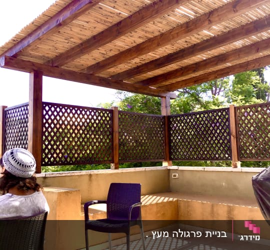 פרגולה מעץ עם גדר עץ מסביב לגינה